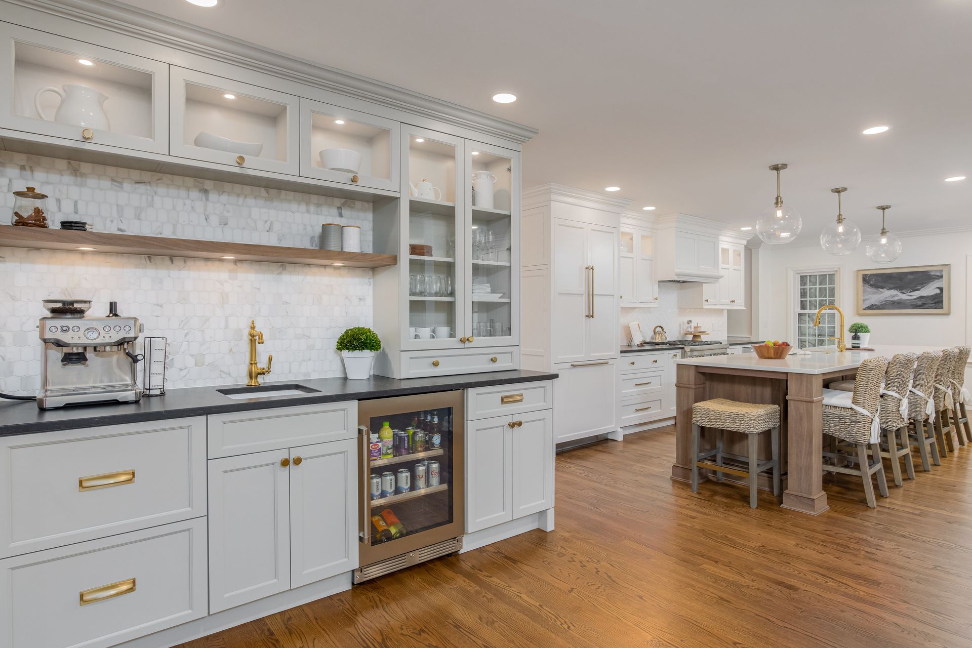 Bright modern kitchen and dining area with white cabinets, wood floors, and a wooden island table