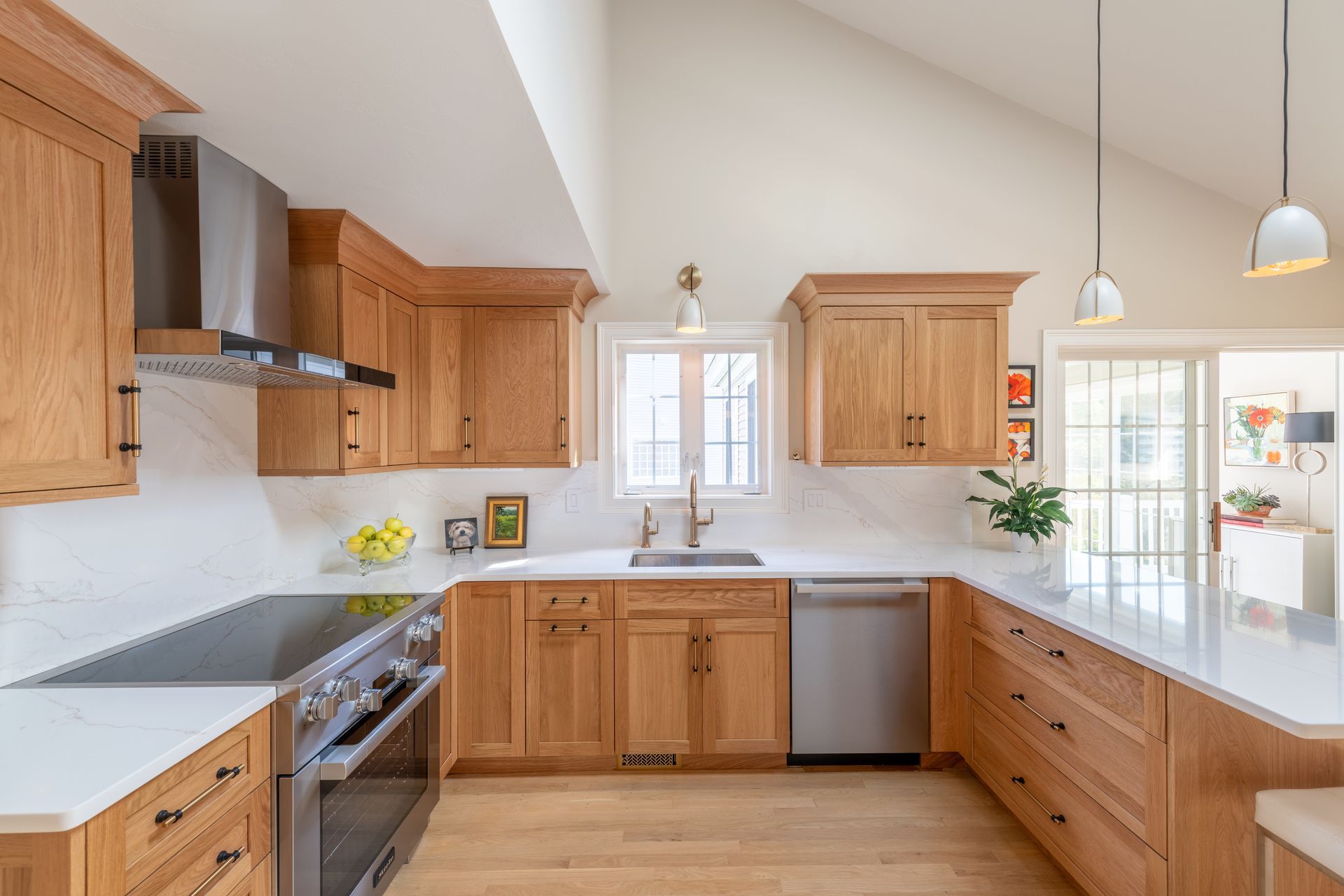 Bright kitchen with wood cabinets, white countertops, stainless appliances, and a central window over the sink