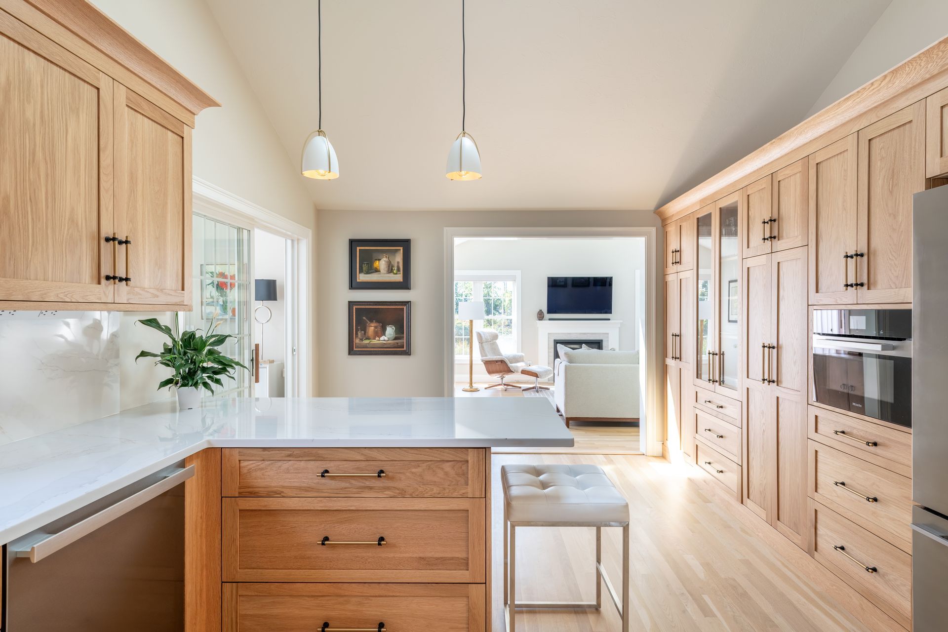 Bright modern kitchen with light wood cabinets, white countertops, and two pendant lights