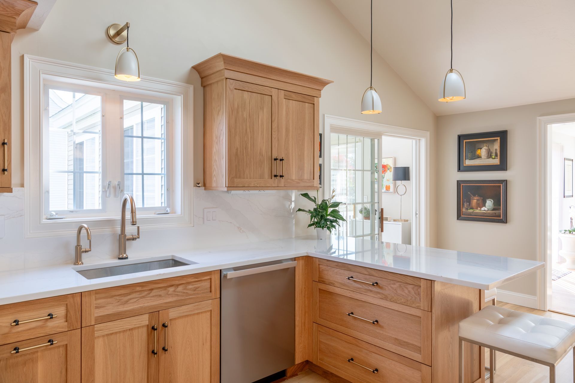 Bright kitchen with light wood cabinets, white countertops, pendant lights, and a window over the sink