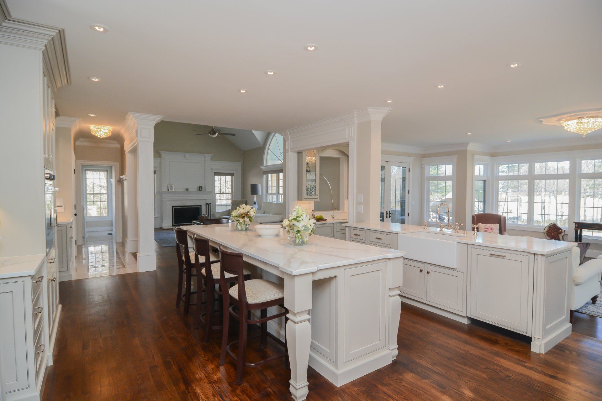 Bright modern kitchen with white cabinets, island seating, and dark wood floors