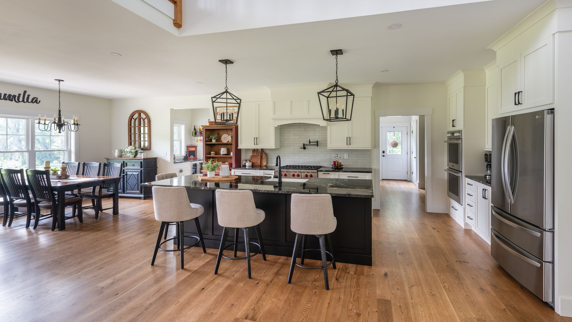 Open-concept kitchen and dining area with island seating, hardwood floors, and stainless steel appliances.