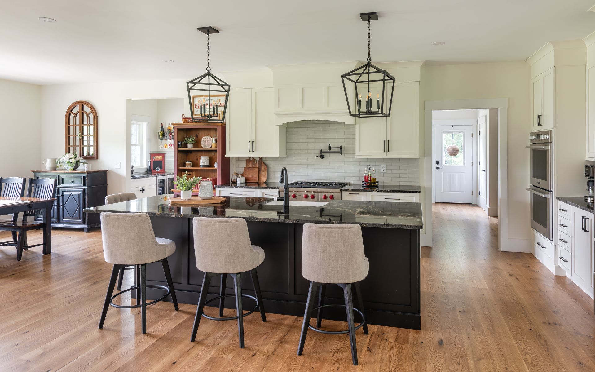 Bright open kitchen with dark island, bar stools, pendant lights, and hardwood floors