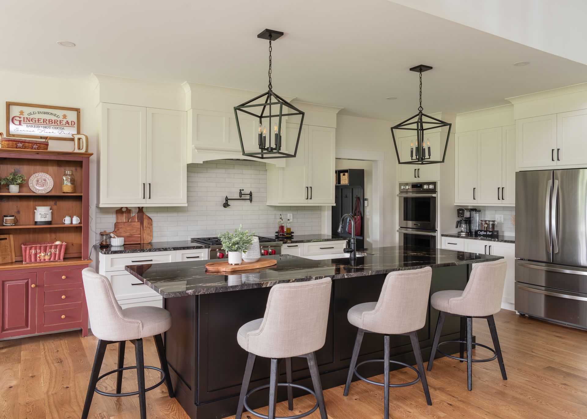 Modern kitchen with white cabinets, black island, pendant lights, and four barstools