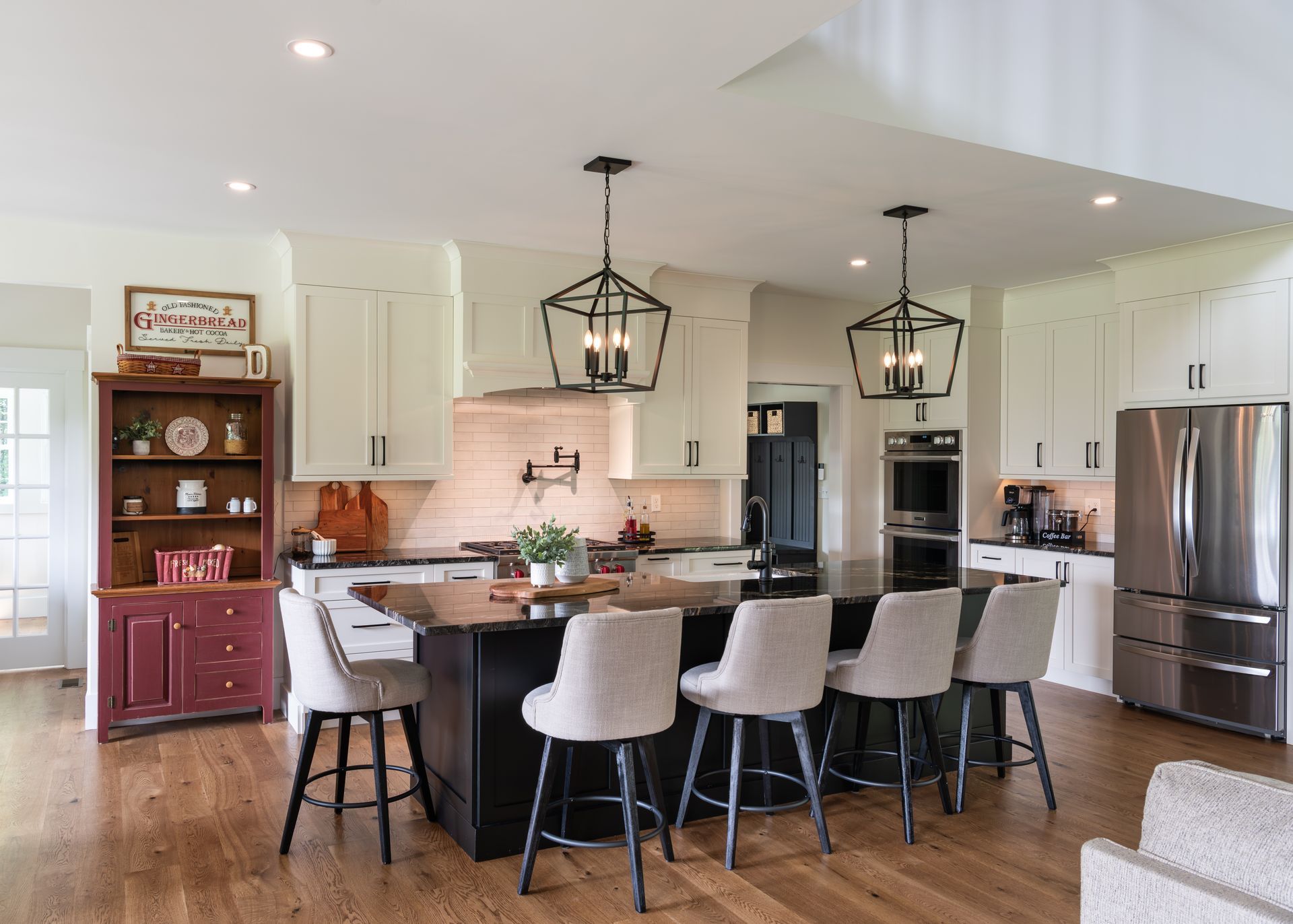 Bright modern kitchen with island seating, pendant lights, stainless steel appliances, and white cabinetry