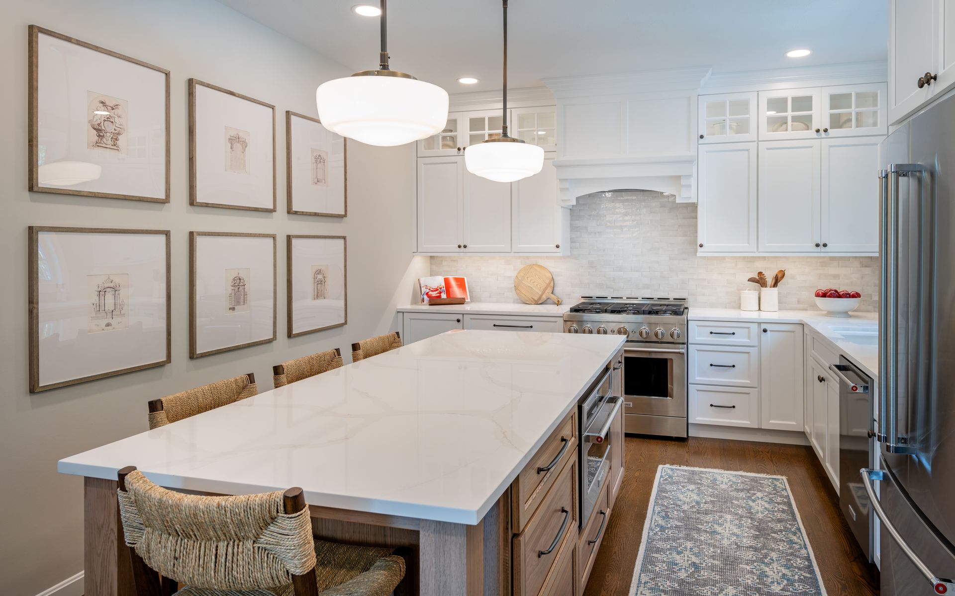 Bright white kitchen with island seating, pendant lights, stainless stove, and stainless refrigerator