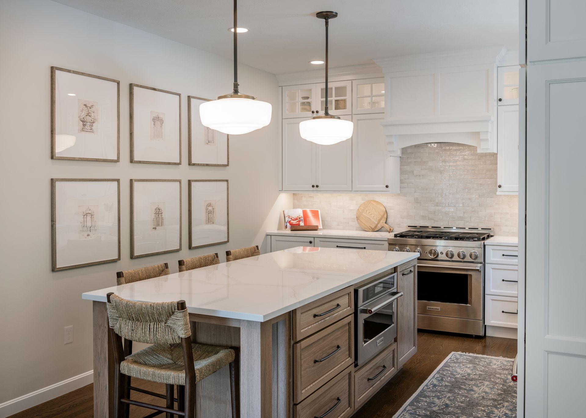 Bright modern kitchen with white cabinets, marble island, pendant lights, and framed art on the wall
