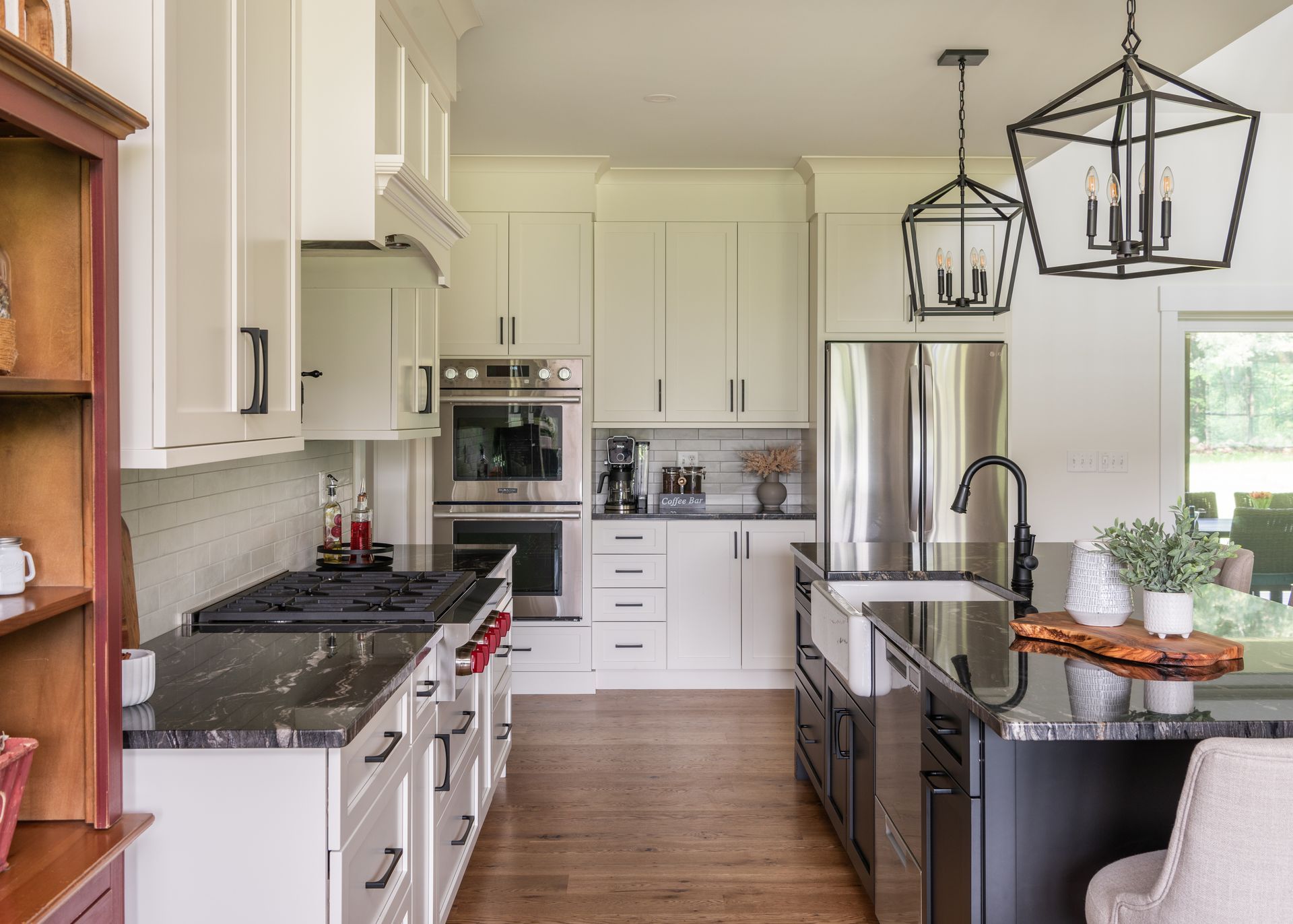 Bright modern kitchen with white cabinets, stainless appliances, wood floor, and black pendant lights