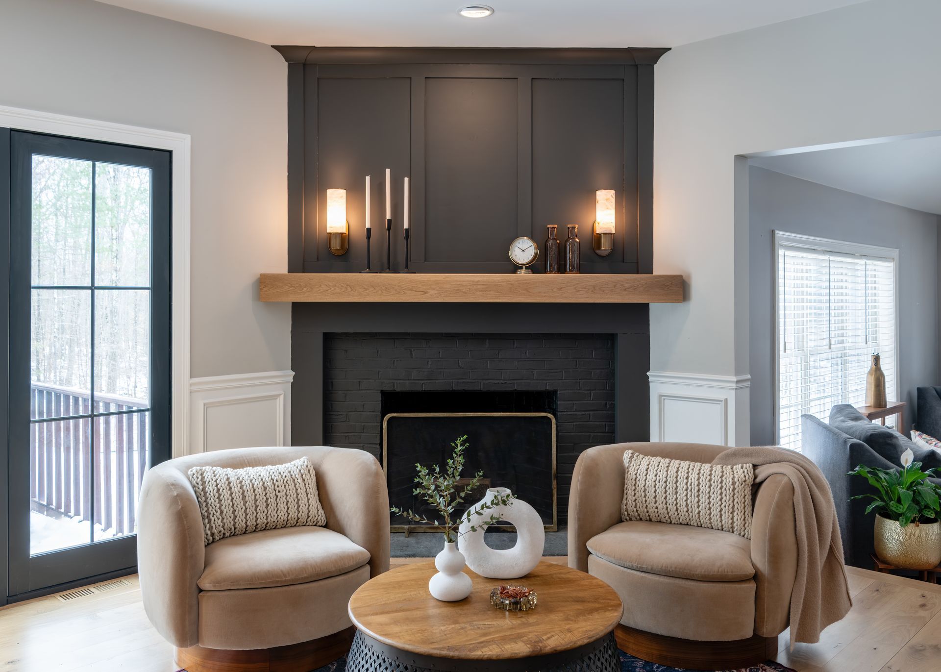 Cozy living room with fireplace, two beige chairs, round coffee table, and soft neutral decor