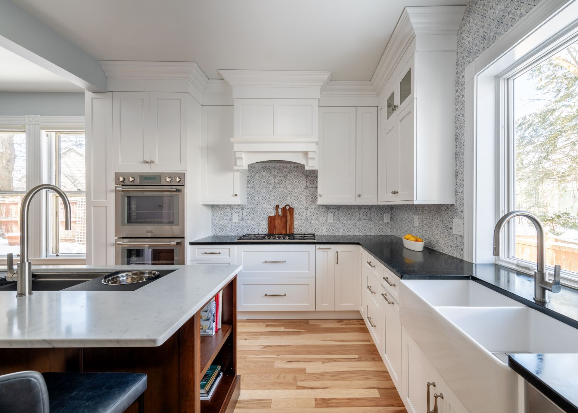 Bright modern kitchen with white cabinets, black countertops, stainless appliances, and hardwood floors