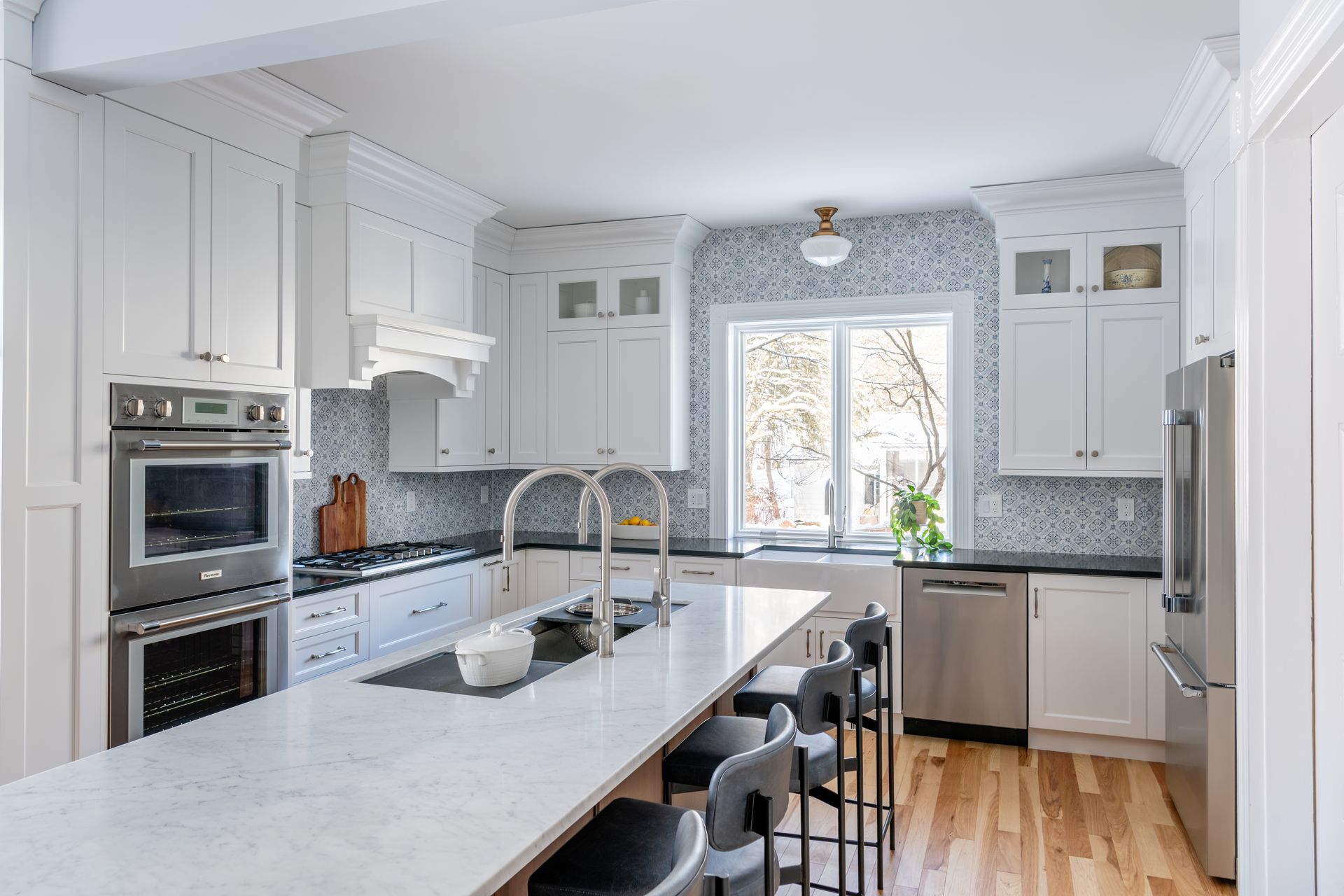 Bright white kitchen with a large island, stainless appliances, and a window over the sink.
