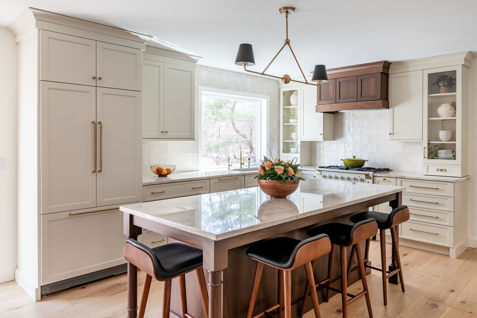 Bright modern kitchen with large island, white cabinets, and bar stools by a window