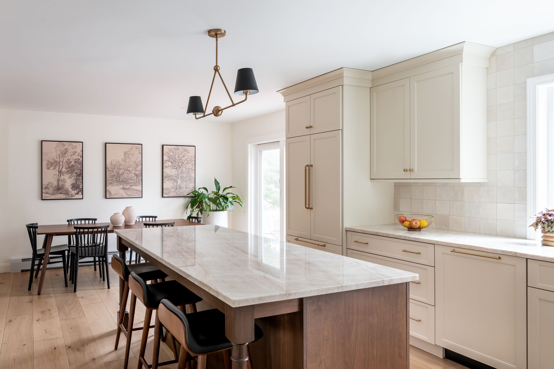 Bright kitchen with large island, cream cabinets, marble countertops, and dining area by the windows.