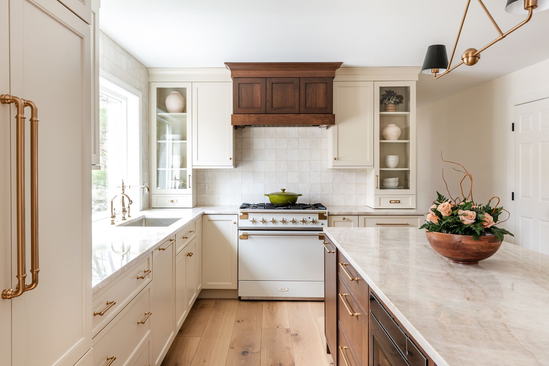 Bright kitchen with white cabinets, wood island, farmhouse sink, and a vase of flowers on the counter