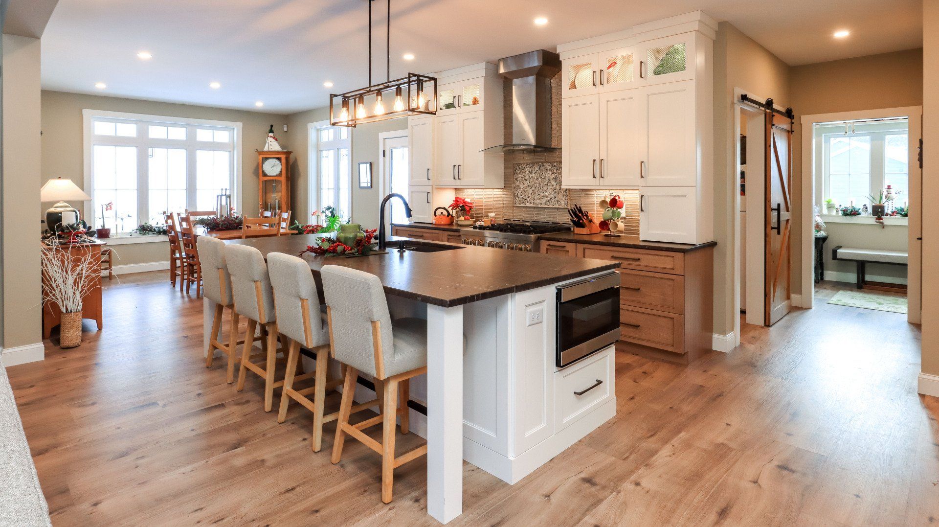 Bright open kitchen with a large island, white cabinets, bar stools, and hardwood floors in a modern home