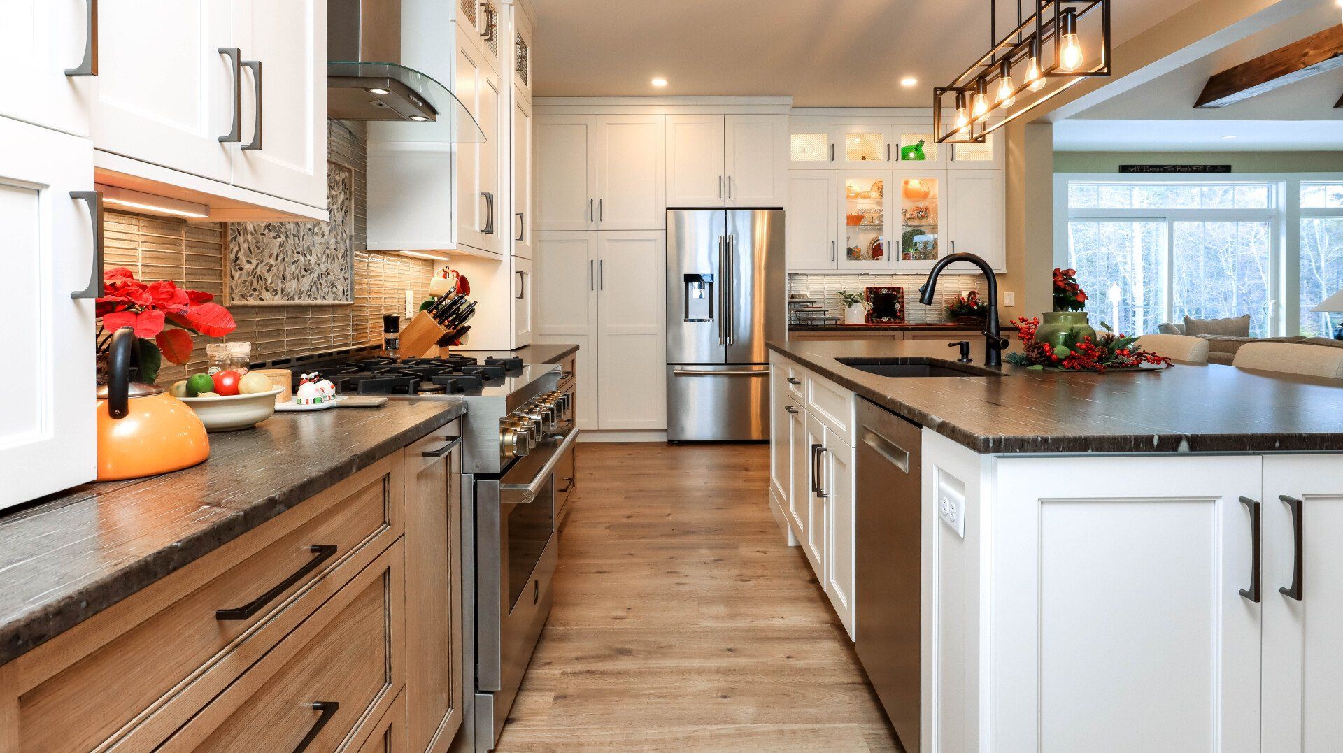 Bright modern kitchen with white cabinets, wood floors, stainless fridge, and black island countertop.