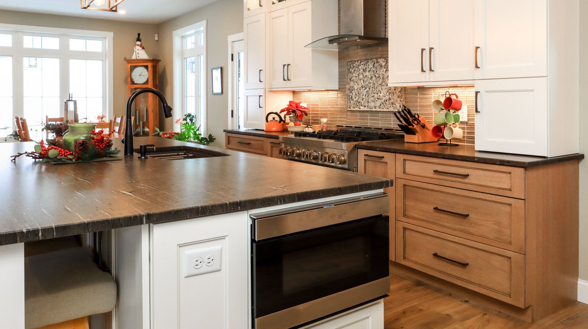 Bright modern kitchen with dark countertops, white cabinets, and a central island with flowers and fall decor