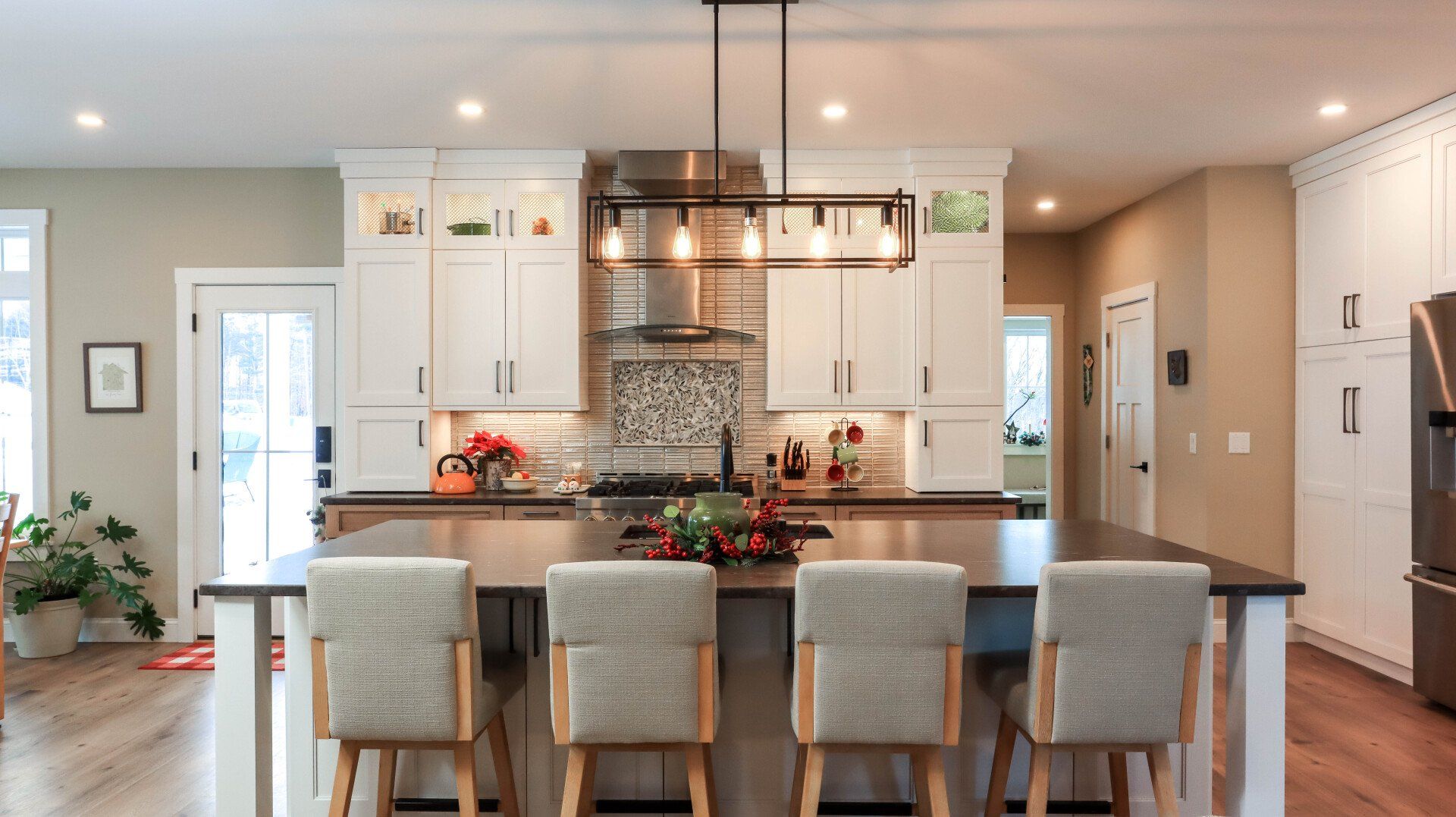 Bright modern kitchen with white cabinets, island seating, pendant lights, and hardwood floors