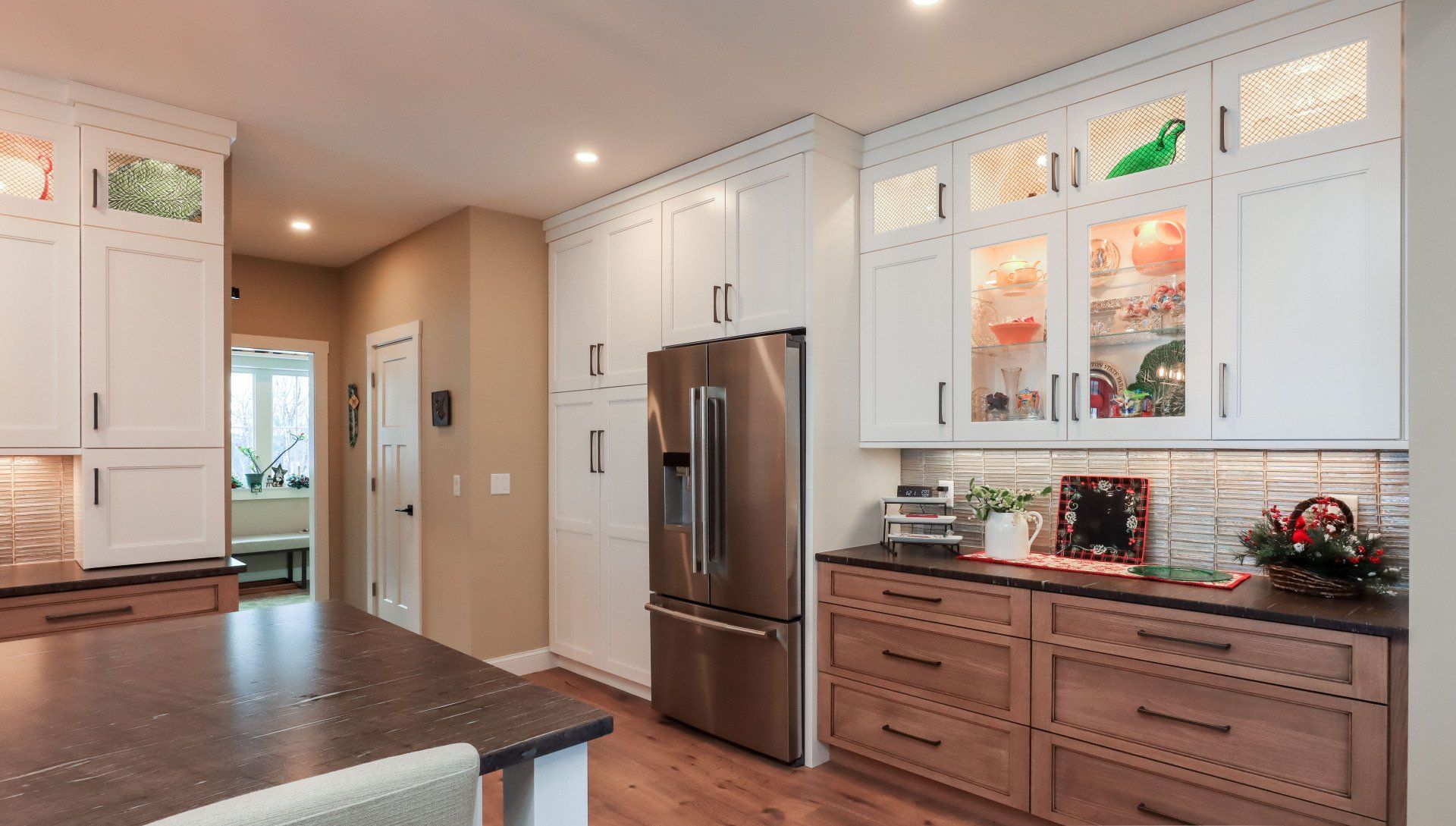 Bright modern kitchen with white cabinets, stainless fridge, and wood island under warm ceiling lights