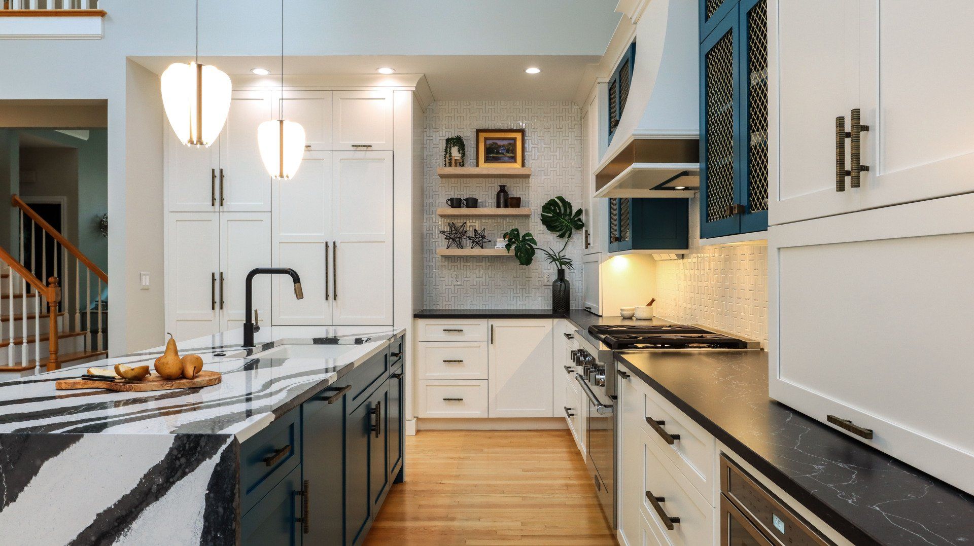 Modern white kitchen with marble island, black accents, pendant lights, and wood floor
