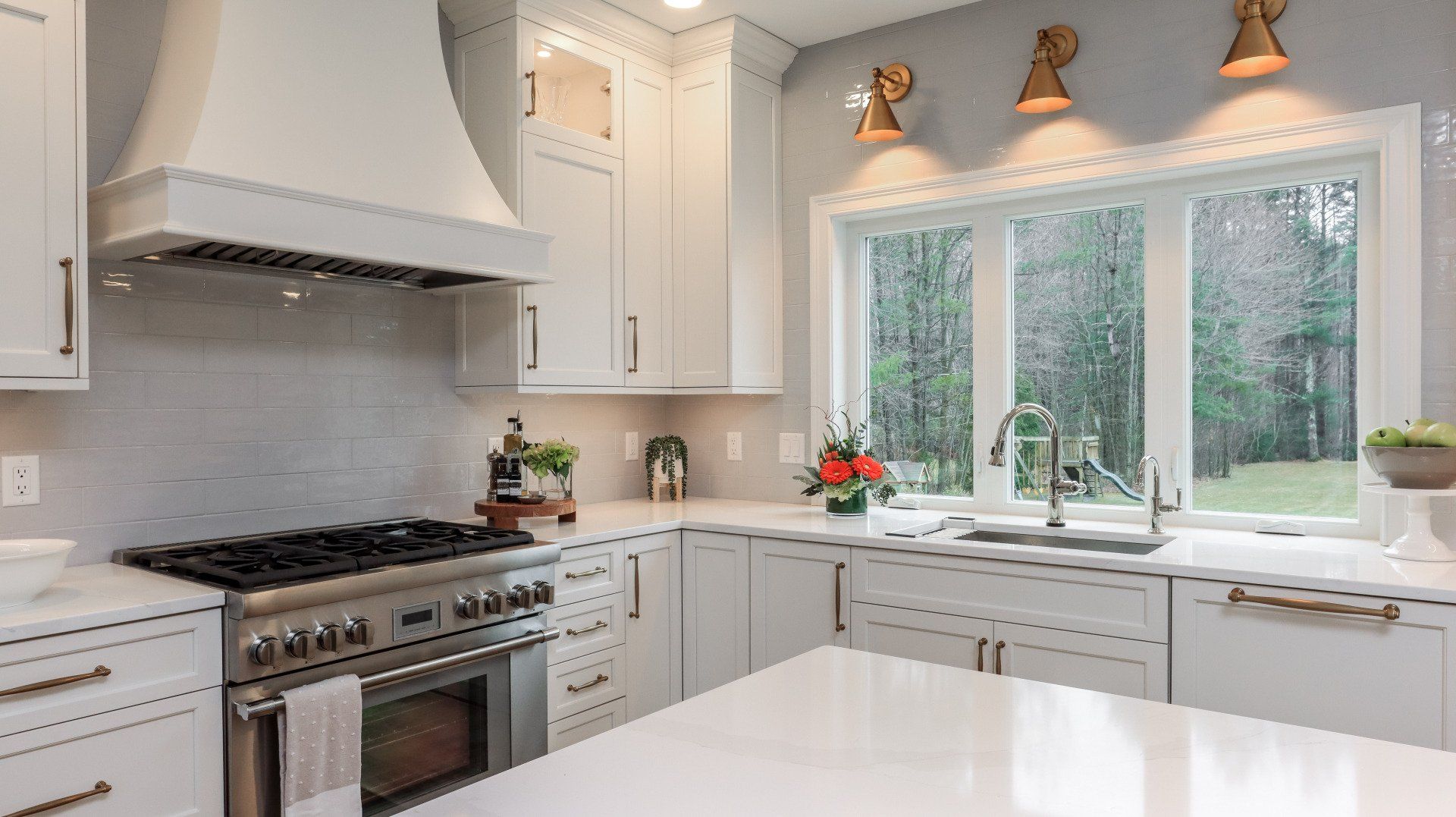 Bright modern kitchen with white cabinets, stainless range, and large window over the sink