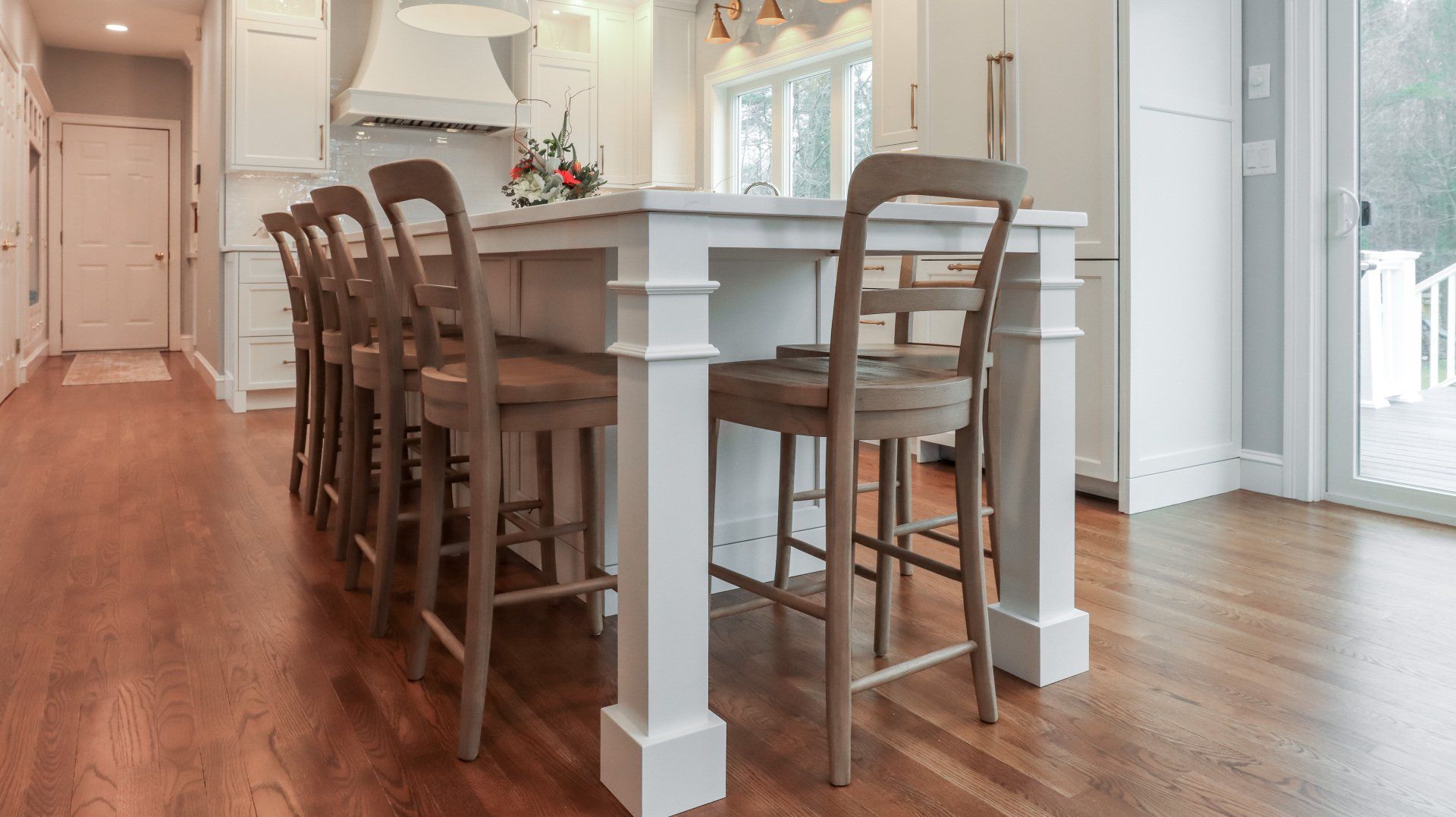 Bright kitchen with a white island, bar stools, hardwood floors, and a sunlit dining area.