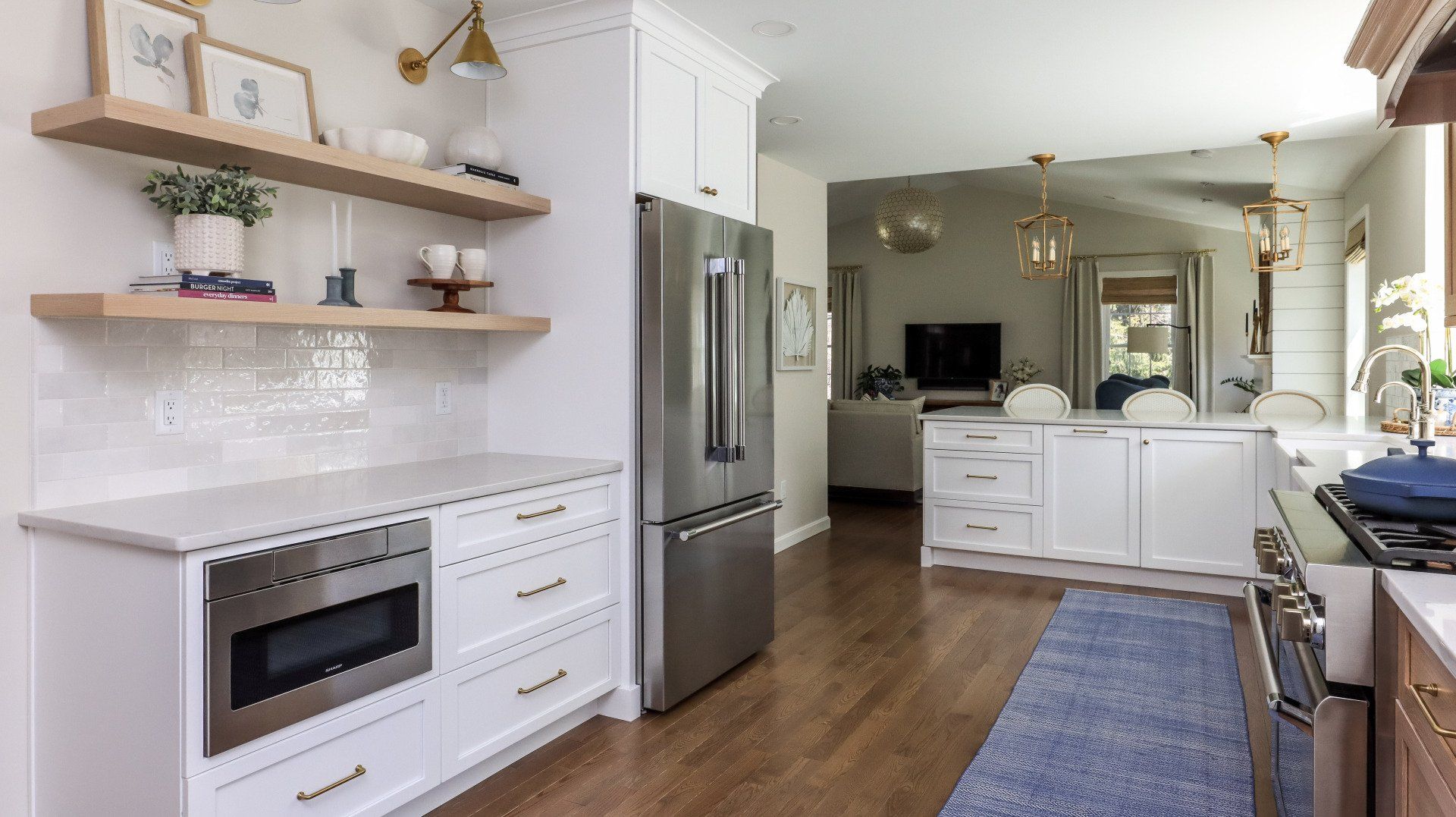 Bright modern kitchen with white cabinets, stainless fridge, wood floors, and open shelves