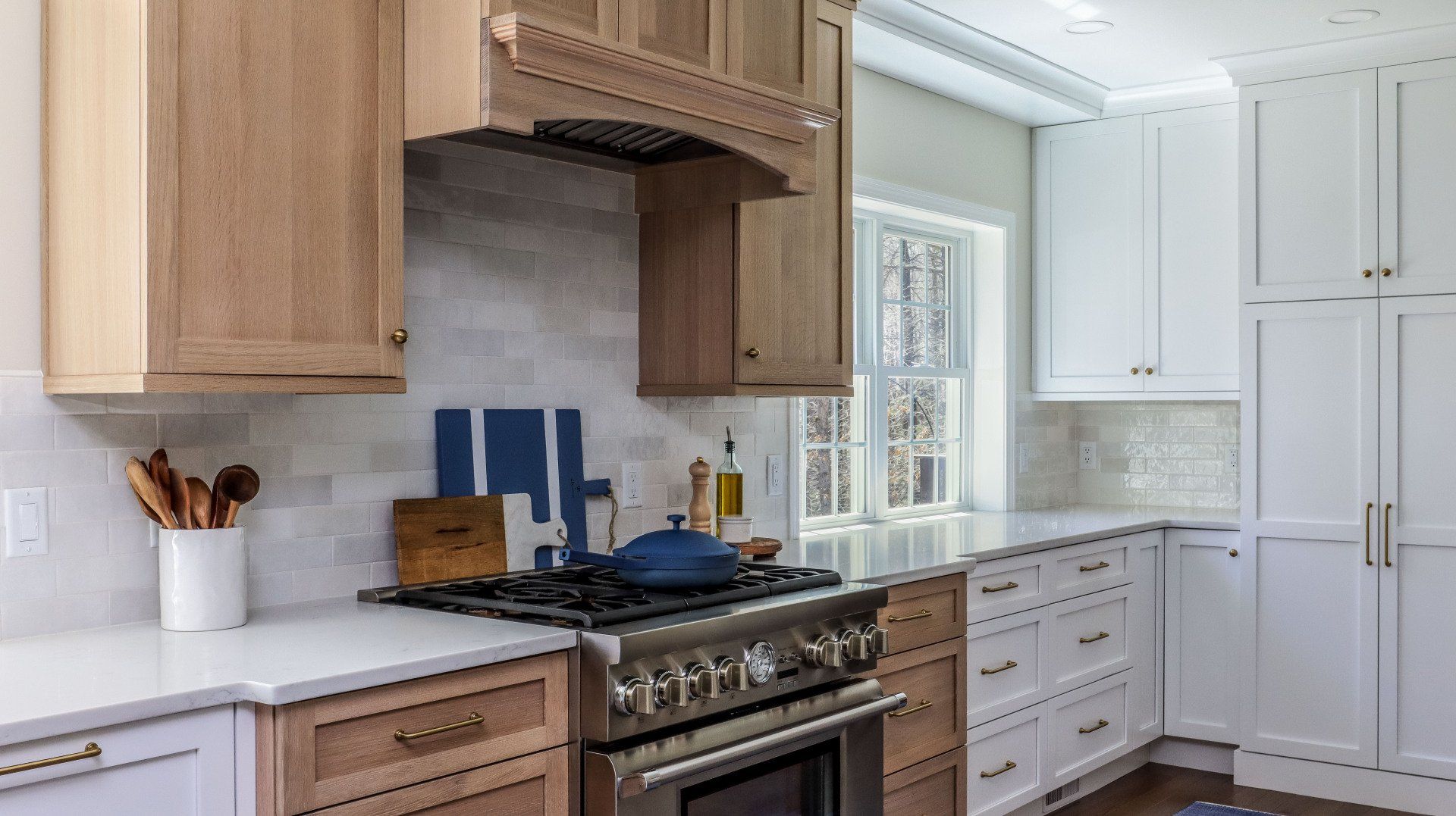 Bright kitchen with wood cabinets, stainless stove, white countertops, and a large built-in refrigerator.