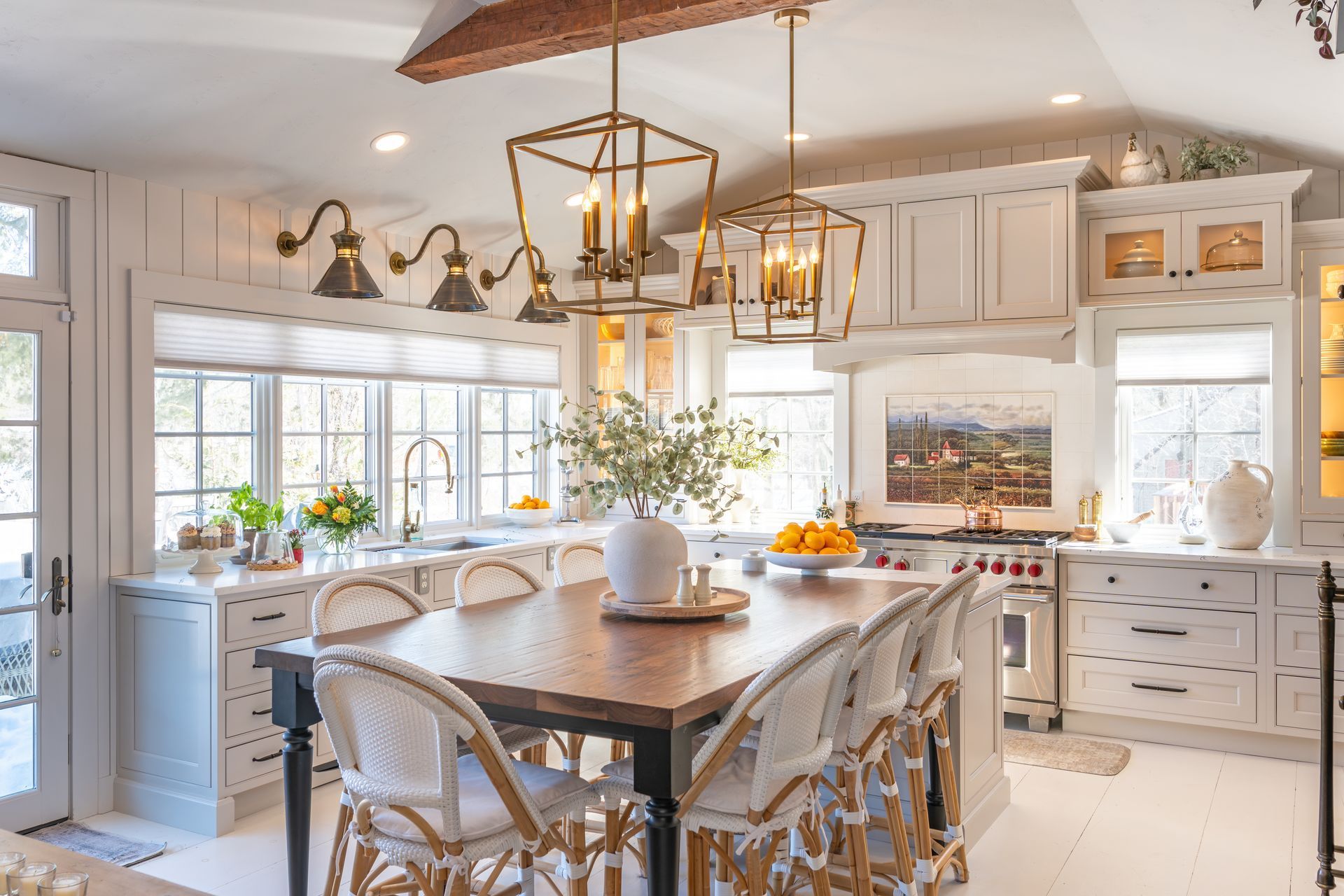 Bright white kitchen with large island, gold pendant lights, and a vase of flowers