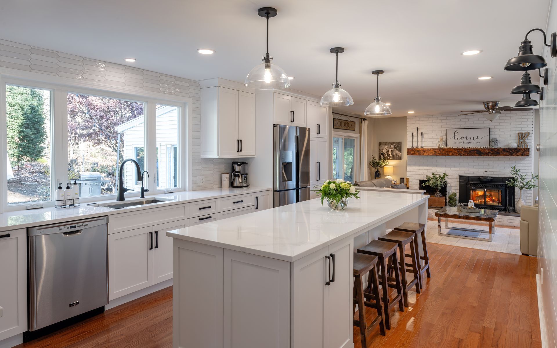 Bright modern kitchen with white cabinets, large island, stainless appliances, and hardwood floors