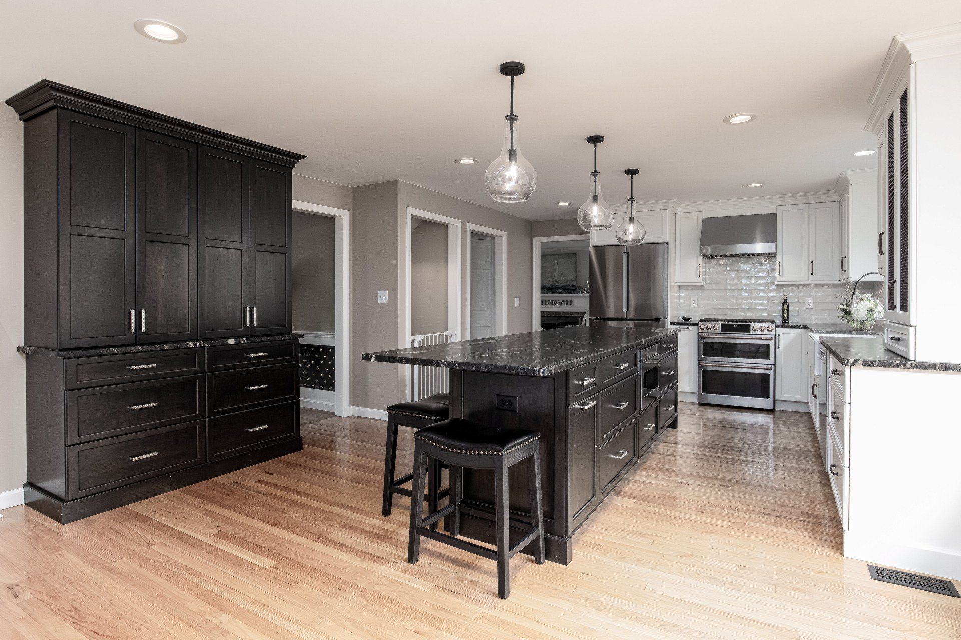 Modern kitchen with black cabinets, stainless steel appliances, island, and hardwood floors