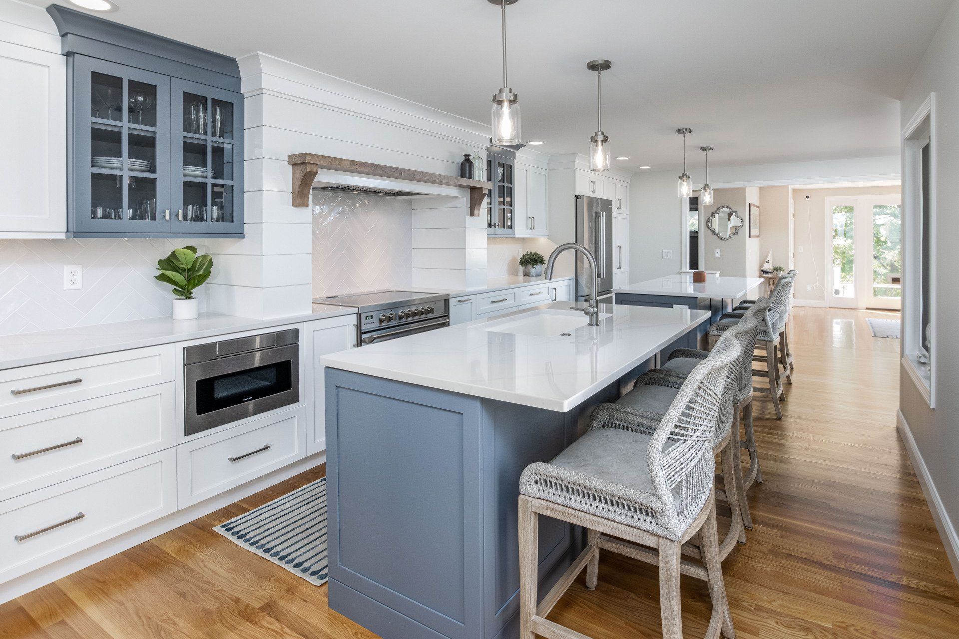 Bright modern kitchen with blue island, white cabinets, pendant lights, and hardwood floors