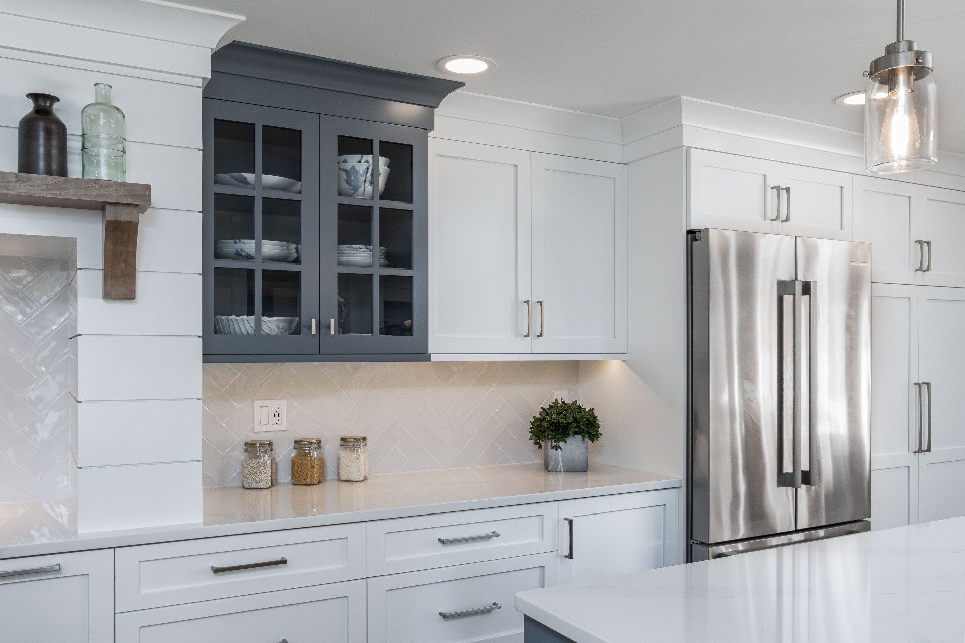 Modern white kitchen with stainless steel refrigerator, gray cabinets, and marble countertop