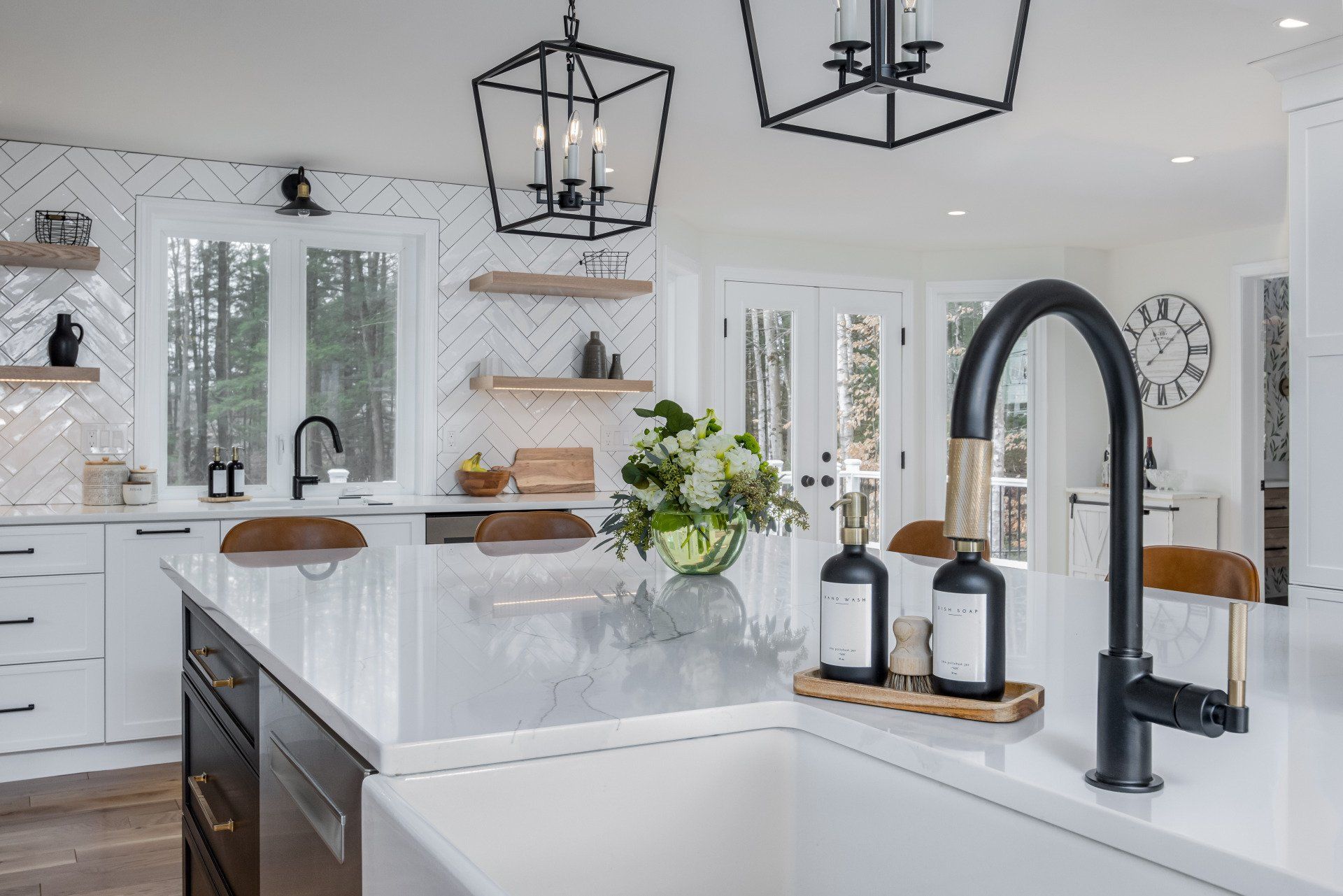 Bright modern white kitchen with marble island, black pendant lights, and large arched faucet