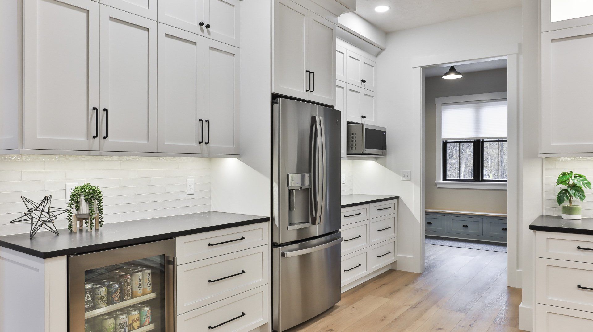 Bright modern white kitchen with stainless steel appliances and light wood floors