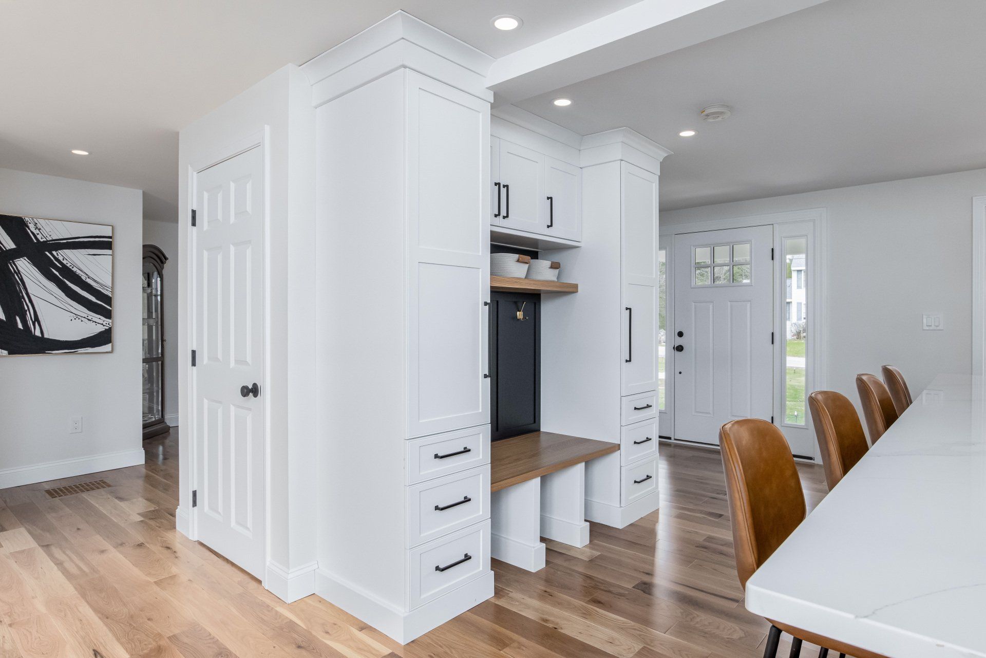Bright white dining area with hardwood floors, built-in cabinets, and a long table with wooden chairs