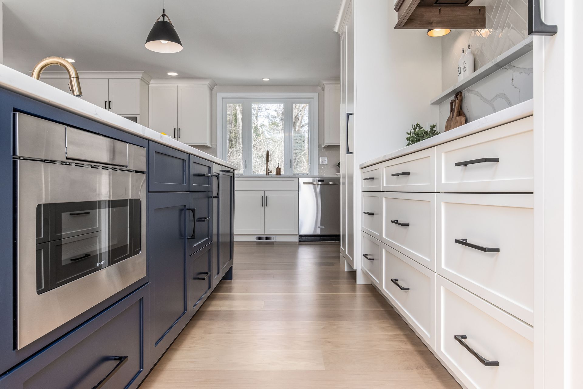 Bright modern kitchen with blue island cabinets, white drawers, and light wood floors