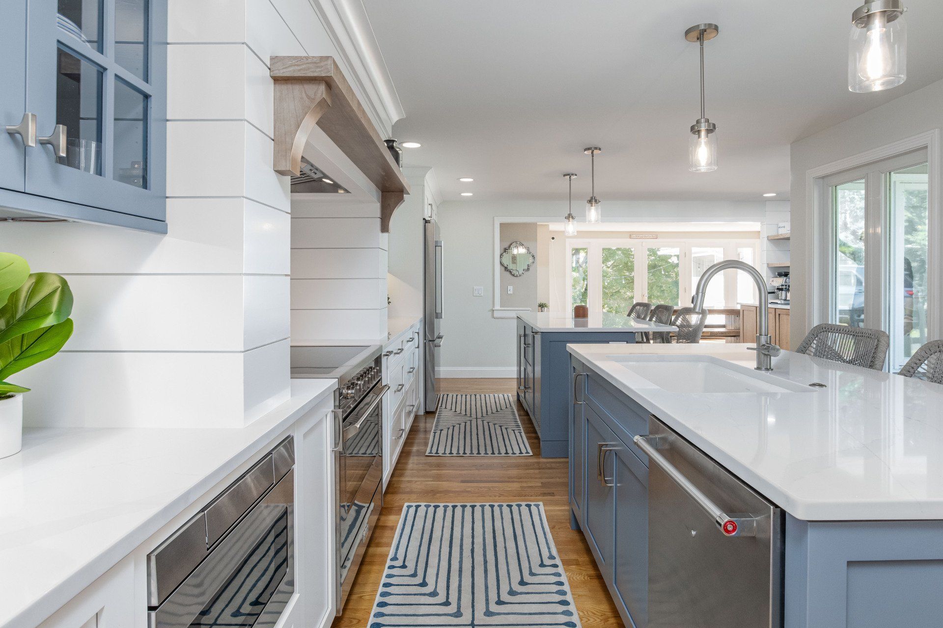 Bright modern kitchen with blue cabinets, white island, stainless appliances, and pendant lights