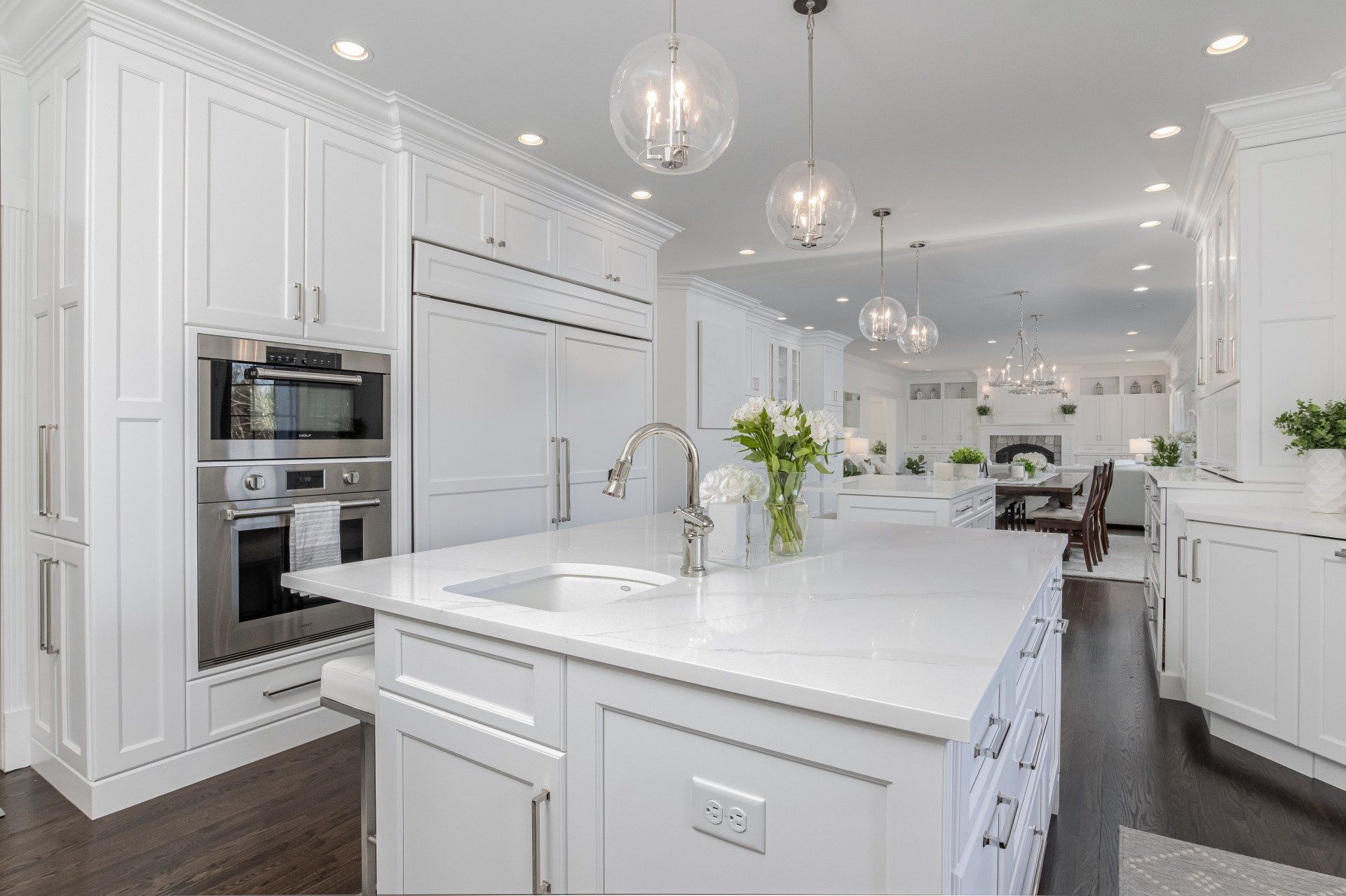 Bright modern white kitchen with island, pendant lights, stainless appliances, and dining area