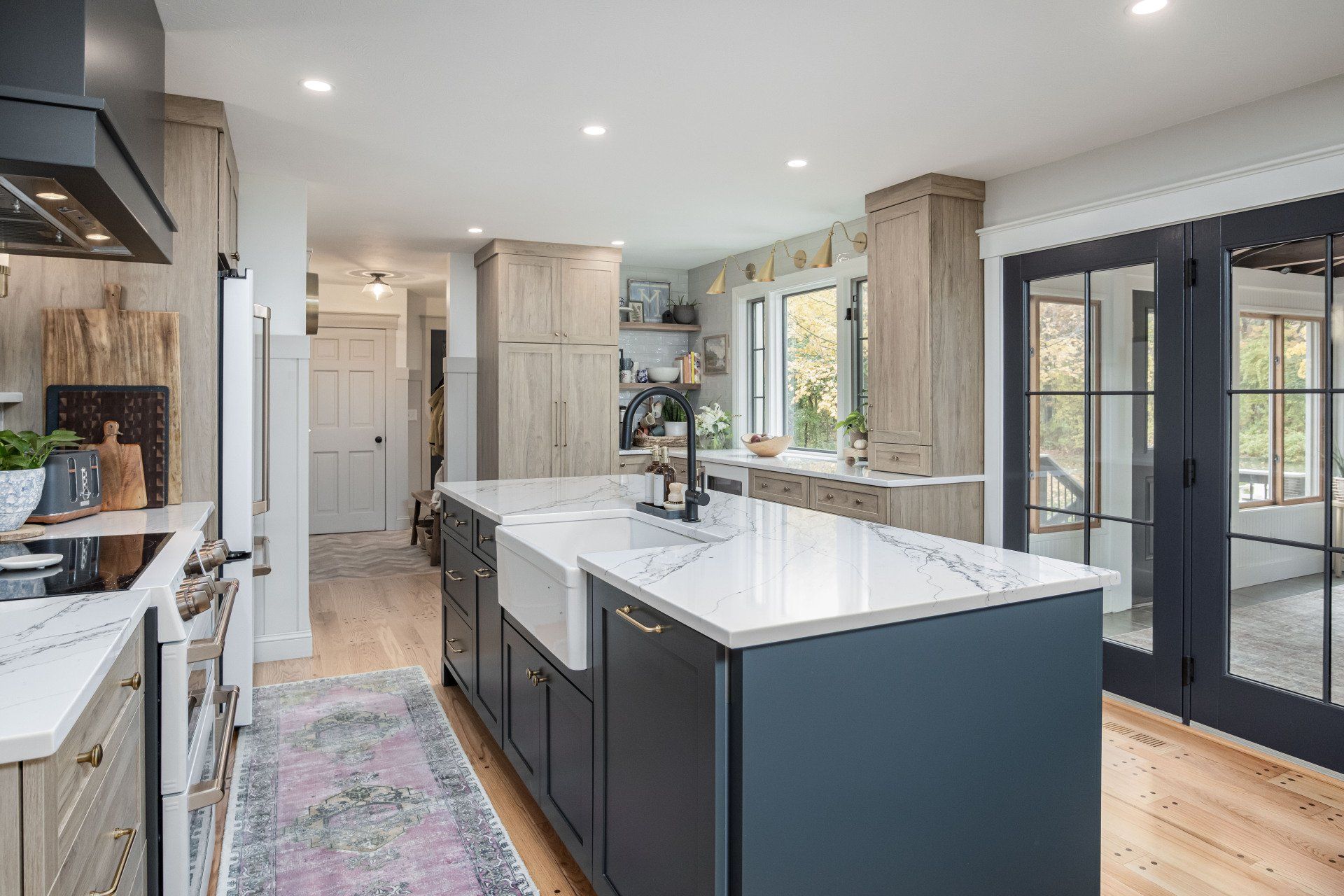 Modern kitchen with large island, white cabinets, dark accents, and French doors to a bright patio.