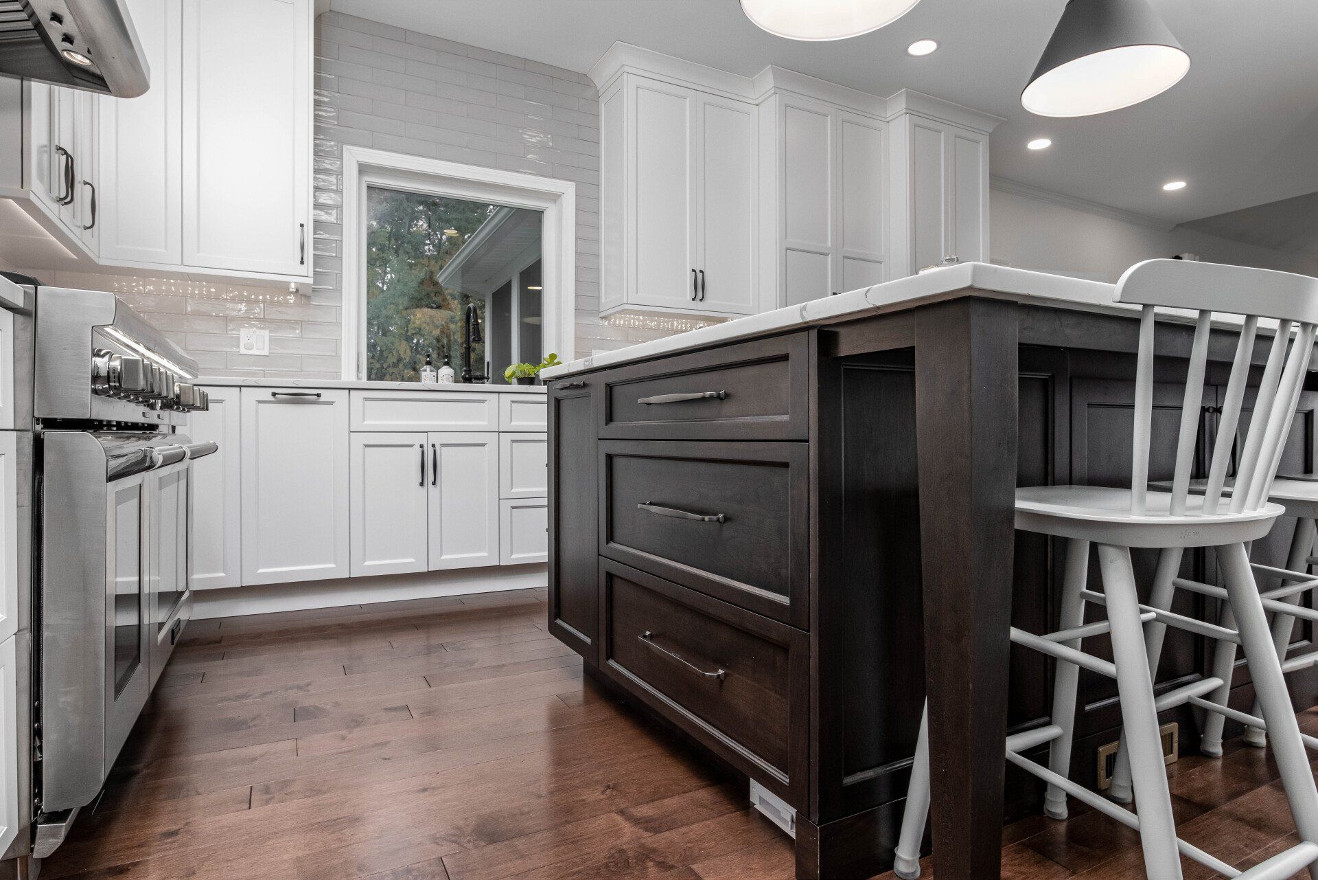 Modern kitchen with white cabinets, dark wood island, stainless appliances, and a window over the sink