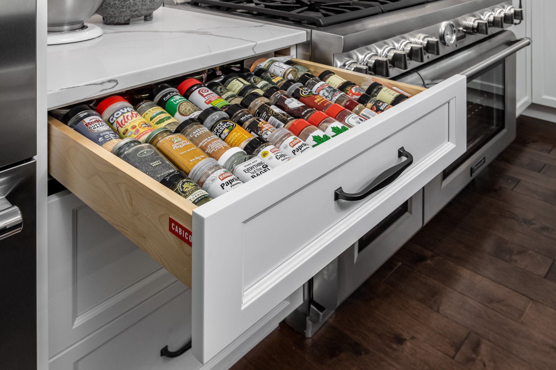Open kitchen drawer filled with neatly arranged spice jars and condiments