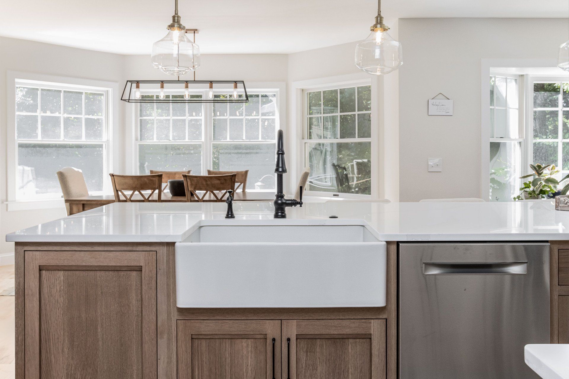 Bright kitchen with a large island, farmhouse sink, pendant lights, and dining area by windows.