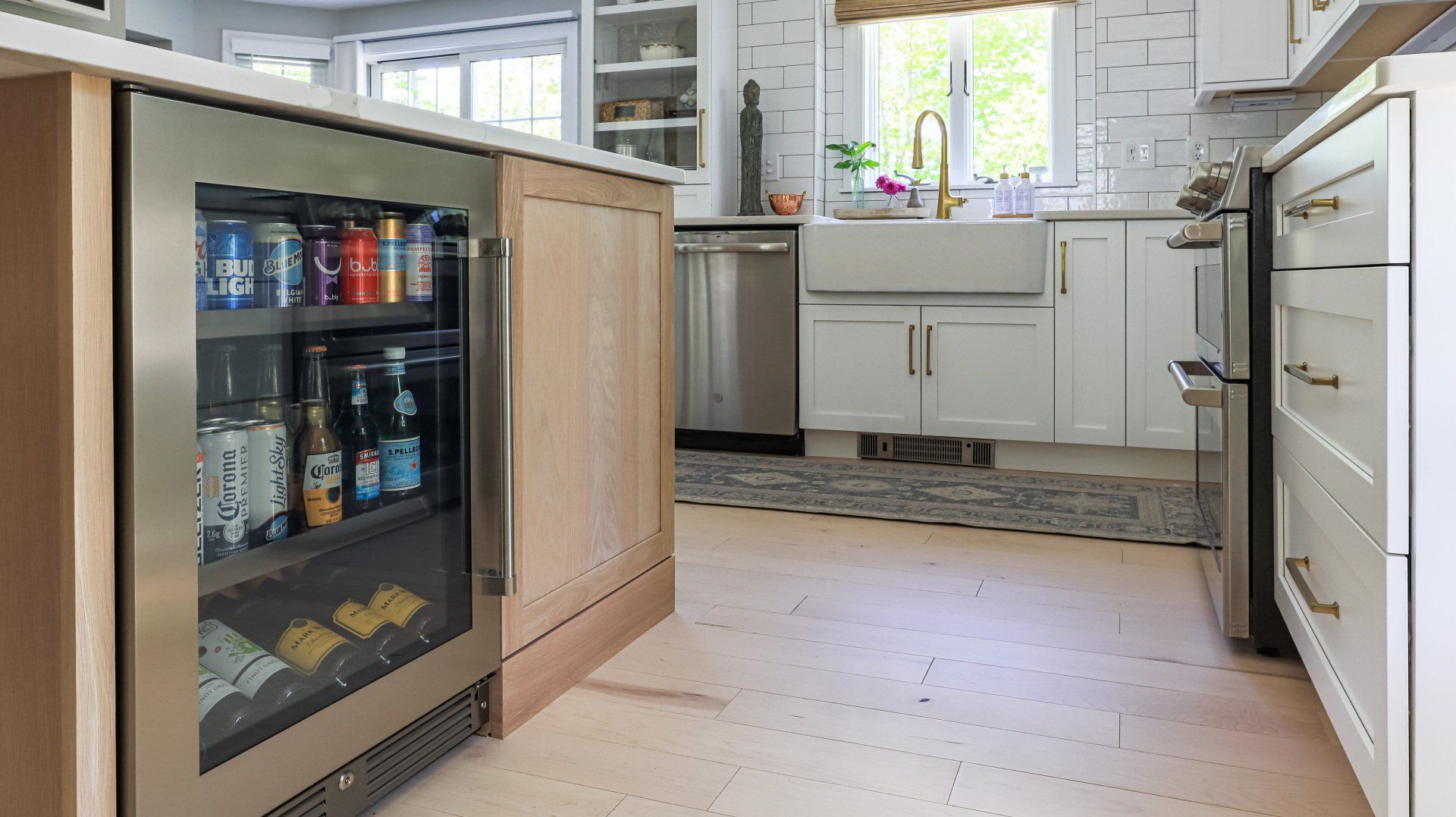 Modern kitchen with white cabinets, stainless appliances, and a small glass-front beverage fridge in the foreground