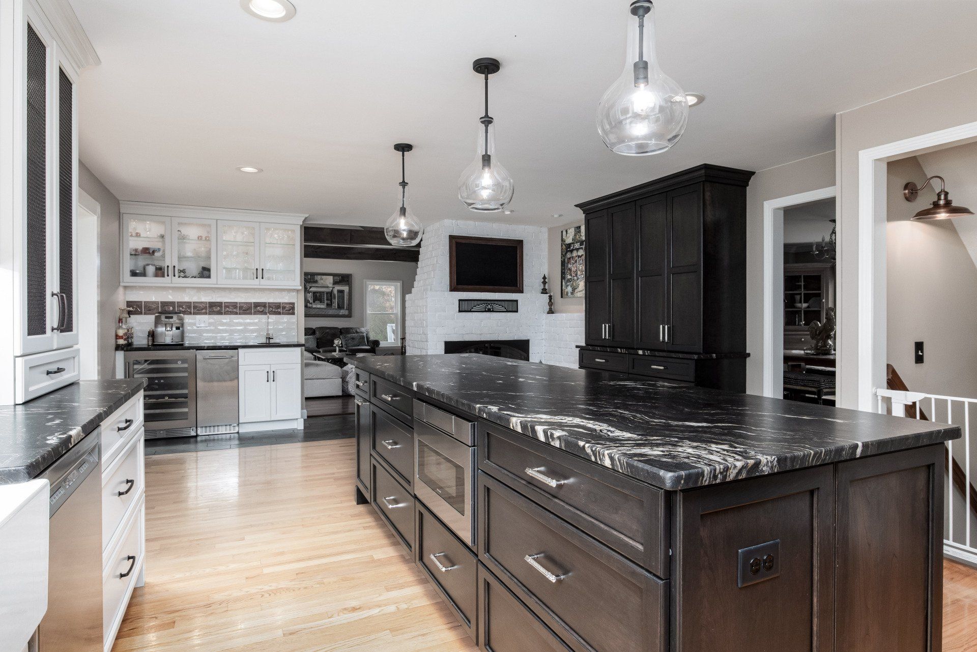 Bright modern kitchen with dark island, white cabinets, stainless appliances, and pendant lights