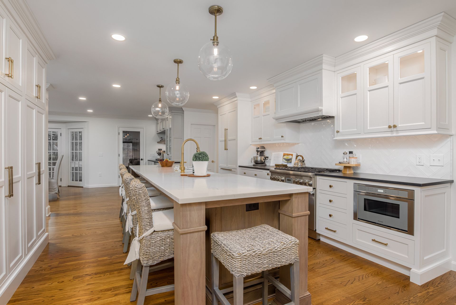 Bright white kitchen with island, bar stools, pendant lights, and hardwood floors