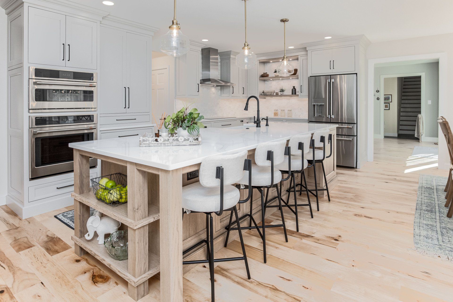 Bright white modern kitchen with island, barstools, stainless appliances, and light wood floors