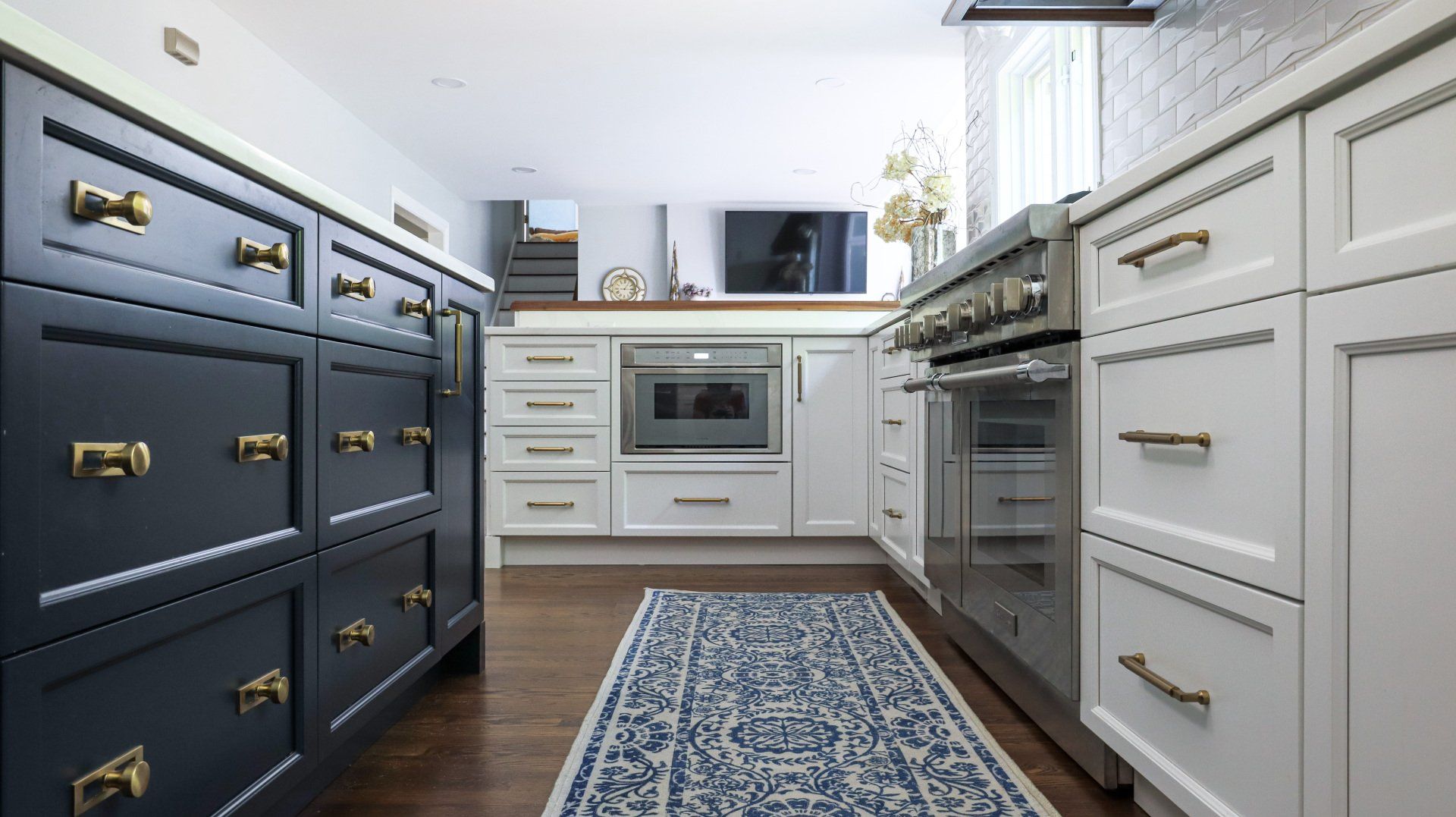 Bright kitchen with navy and white cabinets, stainless appliances, and a blue patterned runner rug.