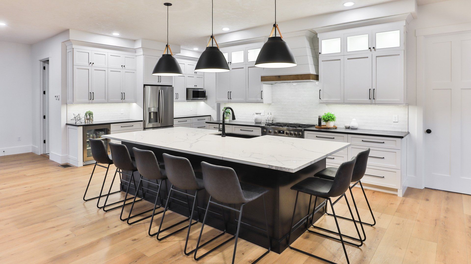 Bright modern kitchen with white cabinets, black pendant lights, and a large island with bar stools