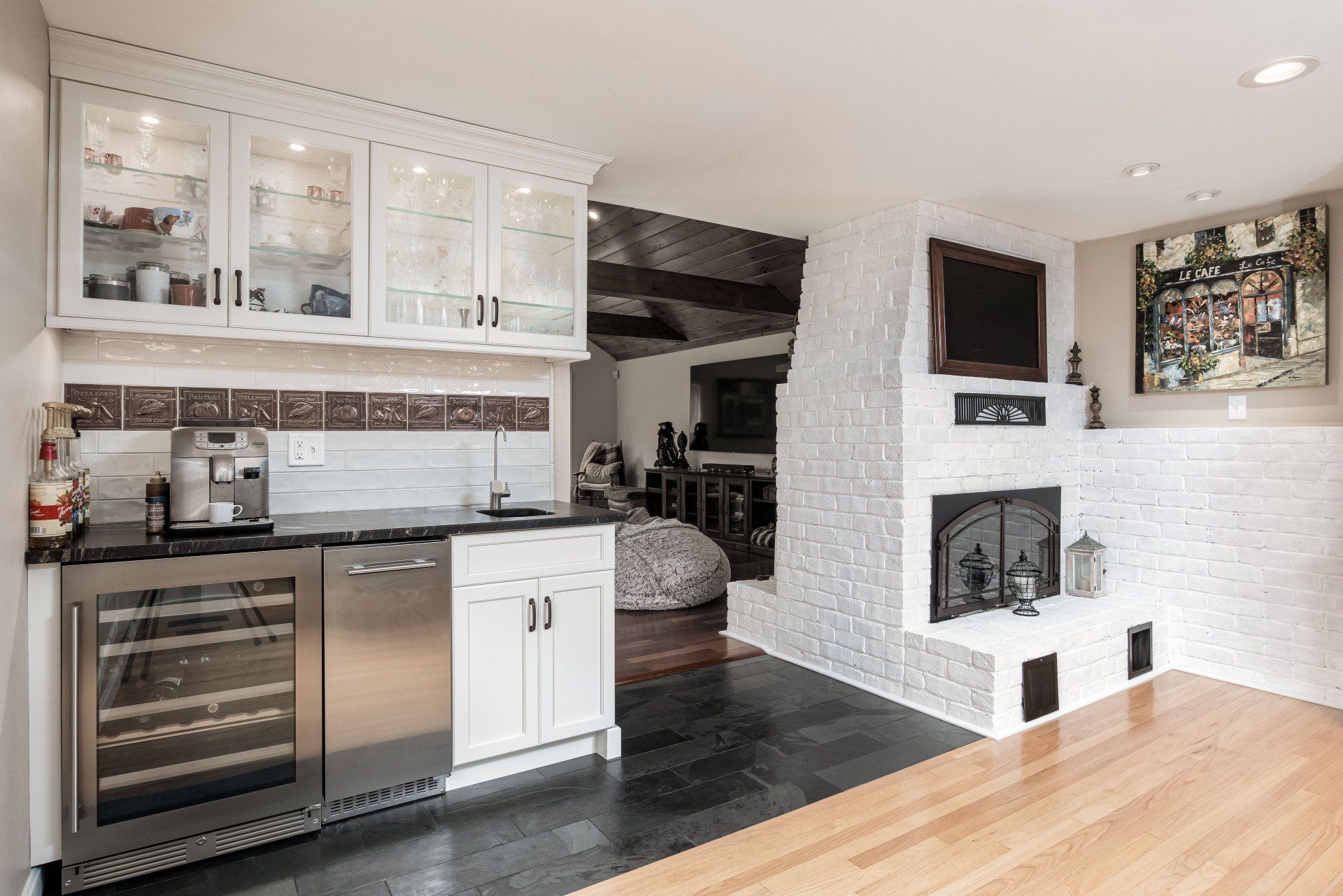 Bright modern kitchen with white cabinets, stainless appliances, and a fireplace in an open living area